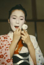 Geisha girl applying make up.