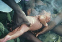 Azande tribe birth ritual where new baby is passed through medicinal smoke.