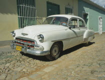 A white Chevy sits amidst the town s features of cobblestone streets.Car Automobile