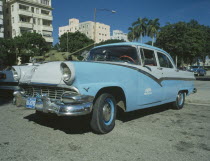 A blue and white taxi parked ouside the Museo de la Revolution with a tank behind.Car Automobile