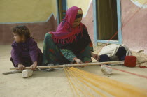 Bedouin mother and daughter weaving on hand loom.