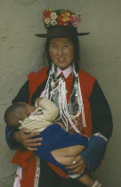 Tu minority Yellow Hat Buddhist woman carrying child wearing open backed trousers instead of nappy.