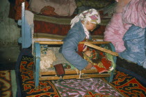 Kazakh woman breastfeeding baby in cot.cradle