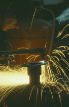 Man wearing protective goggles while welding with sparks flying.