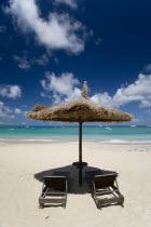 Palapa thatched shelter and sunbeds at Tamarind Beach Hotel in Charles Bay with moored yachts