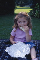 The Bishops Palace Gardens.  Girl aged three eating brown bread and lettuce sandwich during picnic lunch.