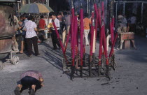 Goddess of Mercy Temple  also known as Kuan Yin Teng.  Exterior with worshippers and large pink burning incense sticks.joss stick