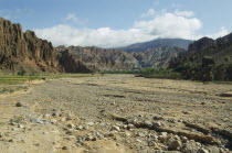 Dry gravel bed of seasonal river in canyon surrounded by high altitude cliffs