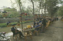 Caged songbirds hanging over outdoor tables and chairs of a tea house.