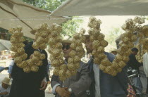 Buyers looking at  Woven bamboo cricket cages strung together and hung up on a stall.