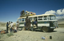 Bus in the countryside being loaded with goods by passengers