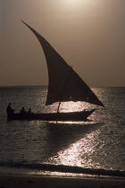 Dhow sailing boat silhouetted at sunset.