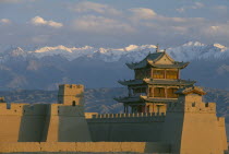 The fortress at the western end of the Great Wall with snow capped mountains behind Silk Road Route