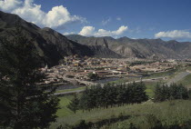 General view over Labrang Monastery from a distance with surrounding hills