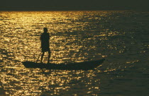Mokoro canoe raft paddler on lake at sunset