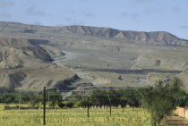 Eroded rocks above wheat field in high altitude remote valley