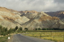 Eroded rocks above wheat field  high altitude remote valley with road in the foreground
