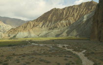 Eroded rocks above wheat fieldin  high altitude remote valley