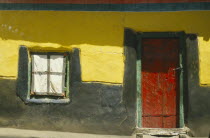 Detail of building with red door set in yellow  black and green wall