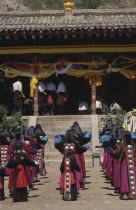 Tibetan Festival at a temple with rows of girls in traditional costume standing before steps
