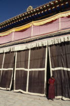Monk standing at the entrance to a Tibetan monastery