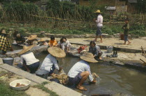 Women and children washing clothes in village stream.