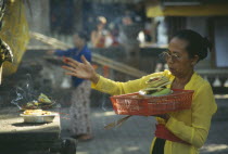 Woman worshipper at small temple  with food offerings