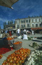 Vegetables for sale on the street in front of three storey buildings at the Sunday MarketSilk Road Route