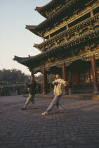 Two men doing morning exercises outside Buddhist temple