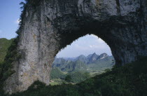View through natural rock archway near the Li River framing mountainous landscape beyond