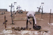 Man in a cemetary cleaning bones that have been removed from a family grave which will be replaced to make room for the next family member