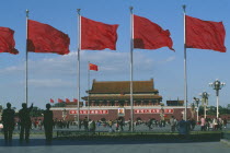 Gate of Heavenly Peace entrance to the Forbidden City in Tiananmen Square behind red flags blowing in the wind