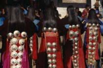 Tibetan dancers at a festival wearing traditional costumes with silver ornamental designs