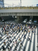 Umeda District Railway Line over a road with traffic under the bridge and a busy pedestrian crossing in the foreground