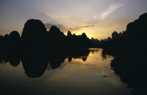 View over River Li lined with towering rock fromations silhouetted at sunset