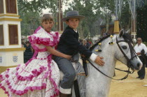 Children in flamenco costume on a grey pony at Jerez horse fair.