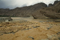Muddy waters flowing through rugged landscape