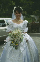 Bride at registry office dressed in traditional western style white dress with veil and bouquet  of orchids.