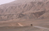 Desert landscape with horse drawn cart heading along dusty track Turpan