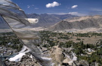 Prayer flags blowing in the wind above village and mountainous terrain