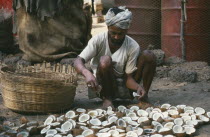 Man laying out cut coconuts to dry in the sun for copra oil