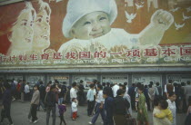 Busy street with pedestrains walking past family planning poster displayed overhead.