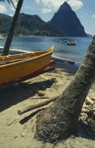 Fishing boat by coconut palm tree on beach with the Pitons in the distance