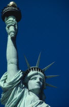 Statue of Liberty. Close up view of the head and raised arm against blue sky