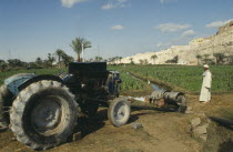 Tractor driven irrigation in field with farmer watching