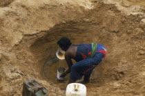 Boran woman digging for water in the sand of a dry river bed