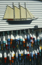 Lobster buoys hanging on wall of clapperboard building beneath a model of a three masted sailing ship