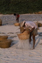 Men sifting sand from sun dried fish in baskets