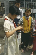 Schoolgirl standing with other children using an abacus.