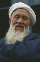 White bearded smiling Kazakhi man in blue wearing white turban Silk Road Route